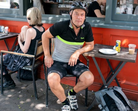 Man in bike helmet and shorts at cafe table