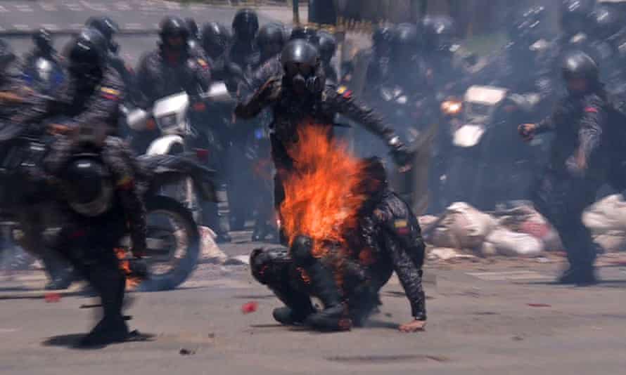 Video grab showing police officers helping a colleague who caught fire after an explosive device went off as they rode past during a protest in Caracas.