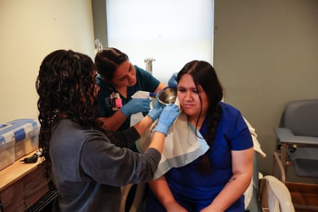 two health workers perform an ear cleaning