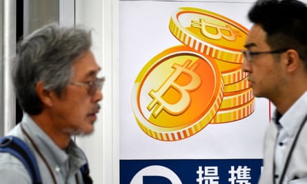 Pedestrians pass a bitcoin currency poster in Tokyo.