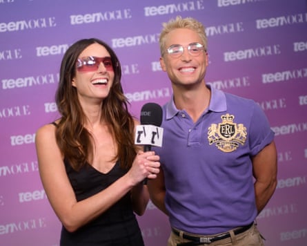 Man and woman in glasses smile on red carpet