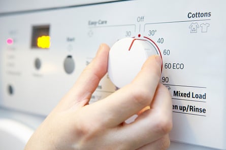 A hand selecting a cooler temperature on a washing machine