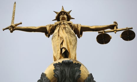 A statue of the scales of justice stands above the Old Bailey, London.