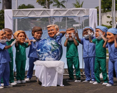 Demonstrators with the likeness of world leaders, including Donald Trump, pretend to perform surgery on the Earth