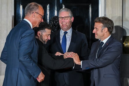 Friedrich Merz looks on as Keir Starmer, Volodymyr Zelenskyy and Emmanuel Macron grasp each other’s hands outside the 10 Downing Street.