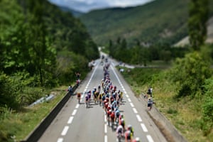 A photograph taken with a tilt-shift lens shows the peloton during the 18th stage of the Tour de France between Vif and Courchevel Col de la Loze in the Alps