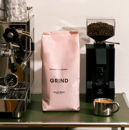 A bag of Grind coffee in between a bean grinder machine and a coffee machine.