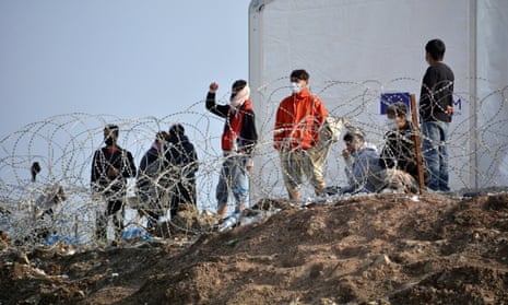 Migrants stand behind a fence at Karatepe refugee camp on Lesbos, Greece, 29 March 2021. 