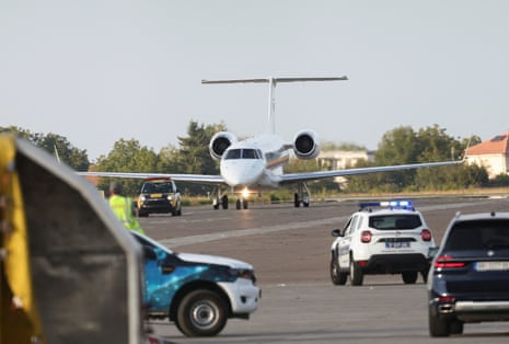 A plane and police vehicles on a runway.