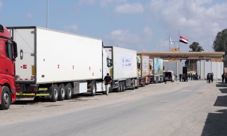 Trucks loaded with humanitarian aid wait on the Egyptian side of the Rafah border