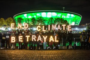 Climate youth activists, Indigenous people, parents, and others hold up huge illuminated letters