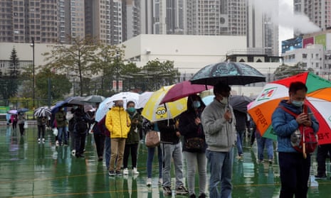 People holding umbrellas line up in the rain at a Covid testing site in Hong Kong.