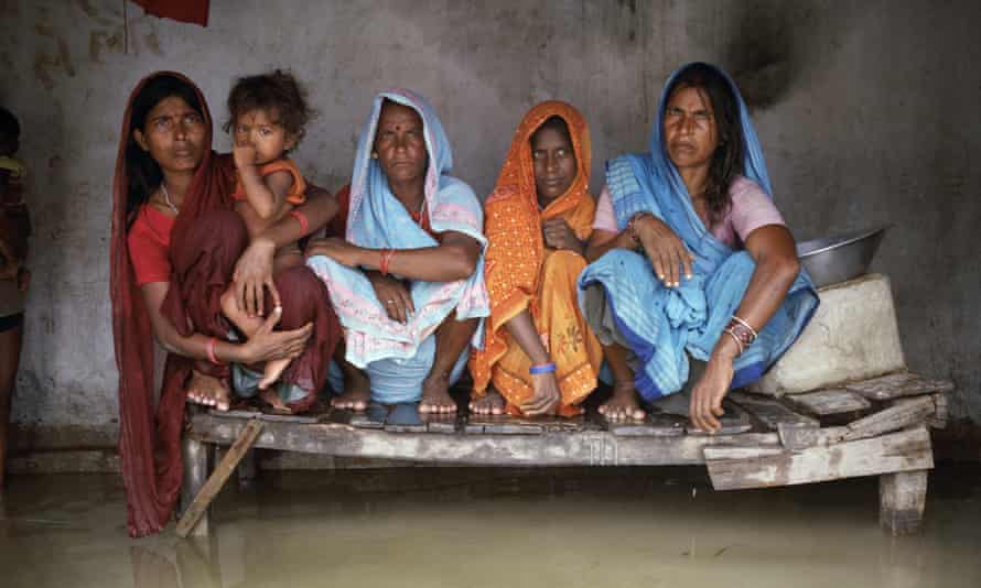Urmila Devi, Sangeeta Devi, Marni Devi and Nago Devi sit on a bed raised just above the floodwaters in the village of Chajan Mania.
