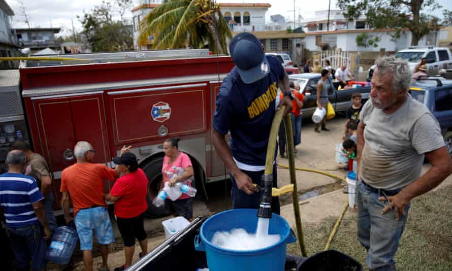 A fireman fills containers with water for residents in Toa Baja, Puerto Rico on Sunday.