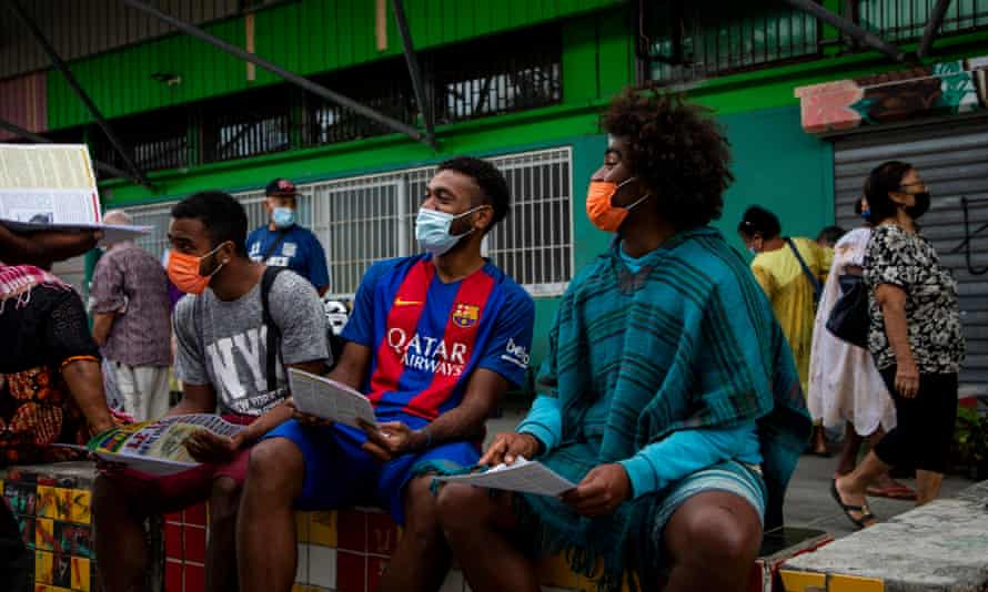 Young men read an independence pamphlet calling for a boycott of the 2021 referendum in the New Caledonian market of Rivière Salée