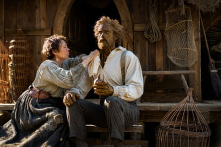 A woman tends to a man with a straw-covered, woven face, from the film Wicker