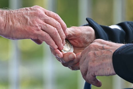 US President Joe Biden slips a challenge coin into the hands of a US WWII veteran during the US ceremony.