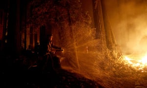A firefighter defends a home during the CZU Lightning Complex Fire in Boulder Creek, California
