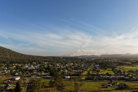 The town of Bulahdelah, NSW, Australia sits north of a bushfire burning in the distance sending smoke into the air.
