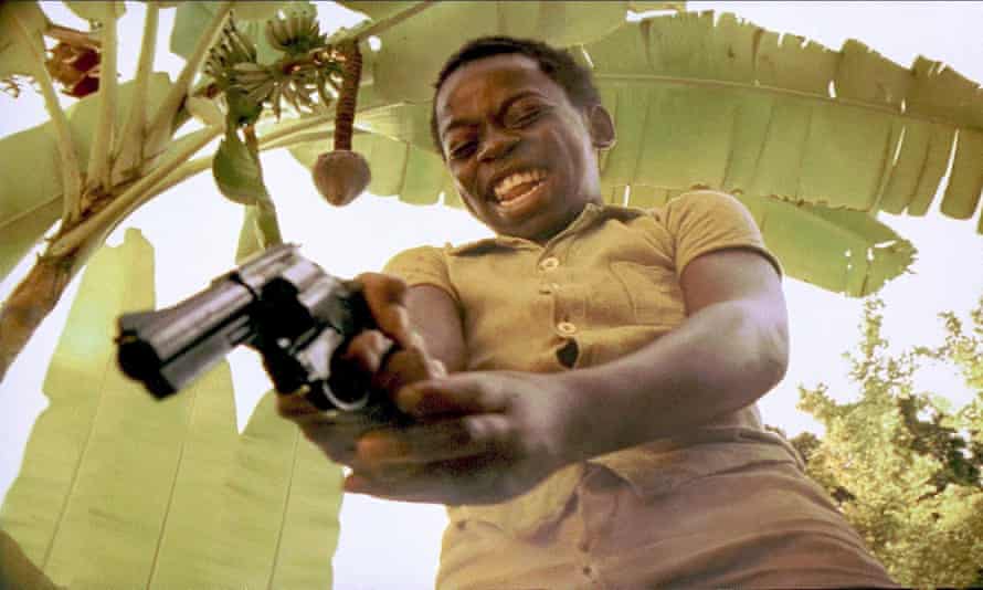 Film still City of God, lead character as a boy pointing a gun and laughing.