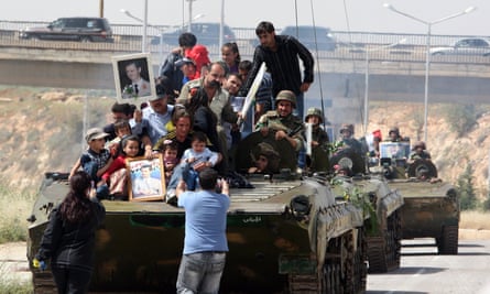 Syrians holding up portraits of President Bashar al-Assad ride on an army personnel carrier in May 2011.