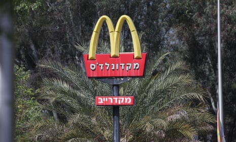 a red and yellow sign with a giant M in front of green trees