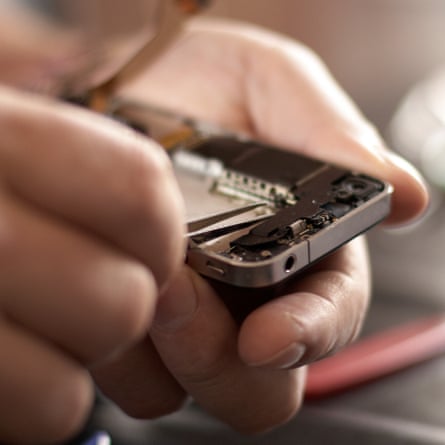 A close up of an electronics engineer repairing a mobile smartphone with a precision screwdriver.
