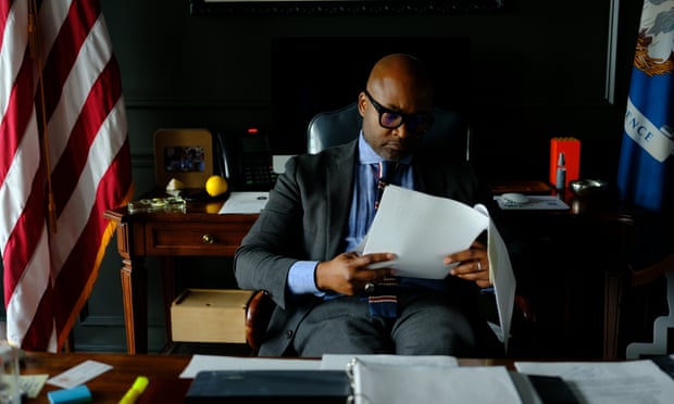 Man wearing a suit reading a stack of stapled papers.