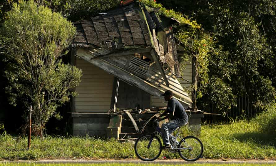 A man bikes past an abandoned house in the Lower Ninth Ward neighborhood of New Orleans.