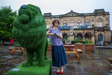Emma drinks an espresso next to a topiary lion