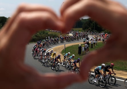 A spectator makes a bosom pinch their fingers while rides walk by connected shape seven