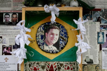 A memorial to Jean Charles de Menezes outside Stockwell Tube station in London, featuring his picture on a Brazil flag and newspaper cuttings.