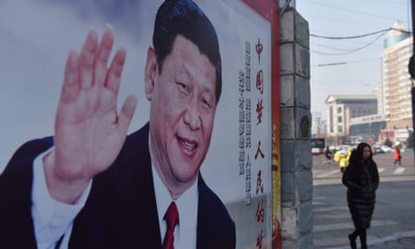 A woman walks past a poster of Xi Jinping beside a street in Beijing.
