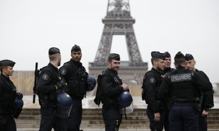 The Eiffel Tower is seen in the background as French gendarmes, part of Operation Sentinelle, patrol the streets