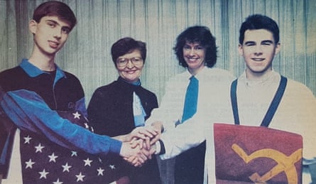 Dmitriev, holding a US flag, and three other people clasp their hands together