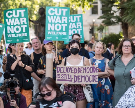 Disabled people and supporters hold placards saying 'cut war not welfare' during a protest against cuts to welfare benefits in Westminster