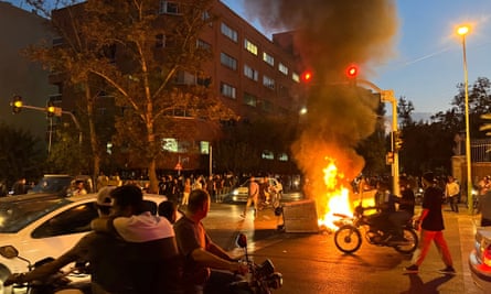 Demonstrators gather around a burning barricade.