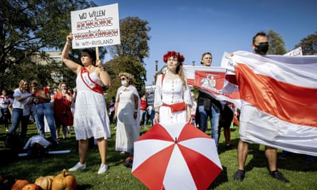 People hold a former white-red-white flag of Belarus as protesters gather in front of the Belarusian embassy in The Hague, the Netherlands.