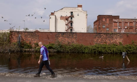 Man walks along the Rochdale Canal in Newton Heath and Miles Platting, Manchester