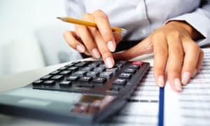 Photo of hands holding pencil and pressing calculator buttons over documents