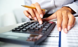 Photo of hands holding pencil and pressing calculator buttons over documents