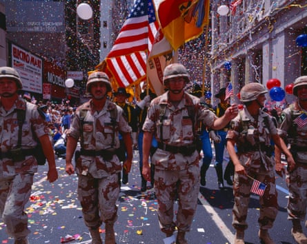 Four soldiers walking with American flag behind them