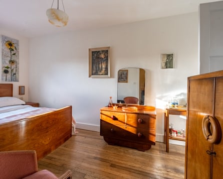 A bedroom with a wooden 1940s double bed, dressing table and wardrobe
