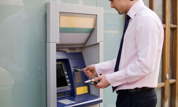A man in smart clothing uses an ATM machine