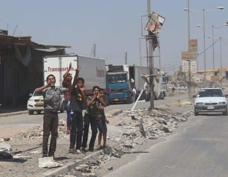 Kids cheer on the passing cars in new Mosul on 11 July.