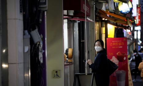 A woman wearing a face mask waits for her food at Dongseong-ro shopping street in central Daegu, South Korea.