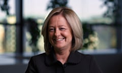 Allison Kirkby: head and shoulders photo showing her in front of a window with blurred view of greenery and sky behind; she is in her mid-50s, has collar-length blond hair, and wears a black jacket.
