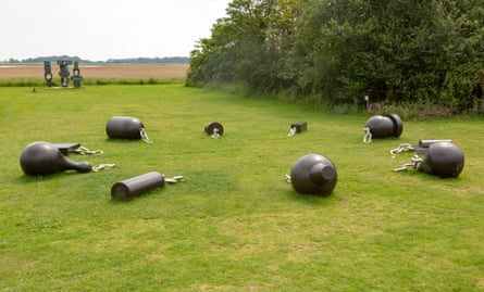 A large outdoor sculpture featuring different shaped iron weights at the end of broken chains, arranged in a circle