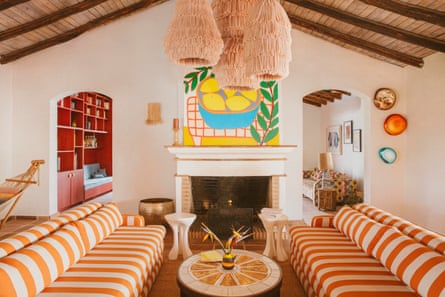 A living room with bold orange and cream striped sofas in front of a fireplace.