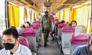A police officer warns passengers to maintain physical distancing inside a bus at a checkpoint in the outskirts of Quezon City, Philippines on 10 January.